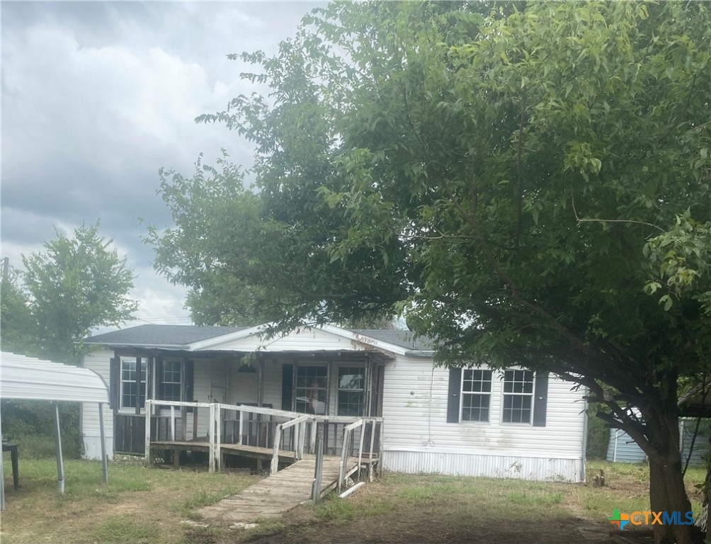 a view of a house with a yard and large tree