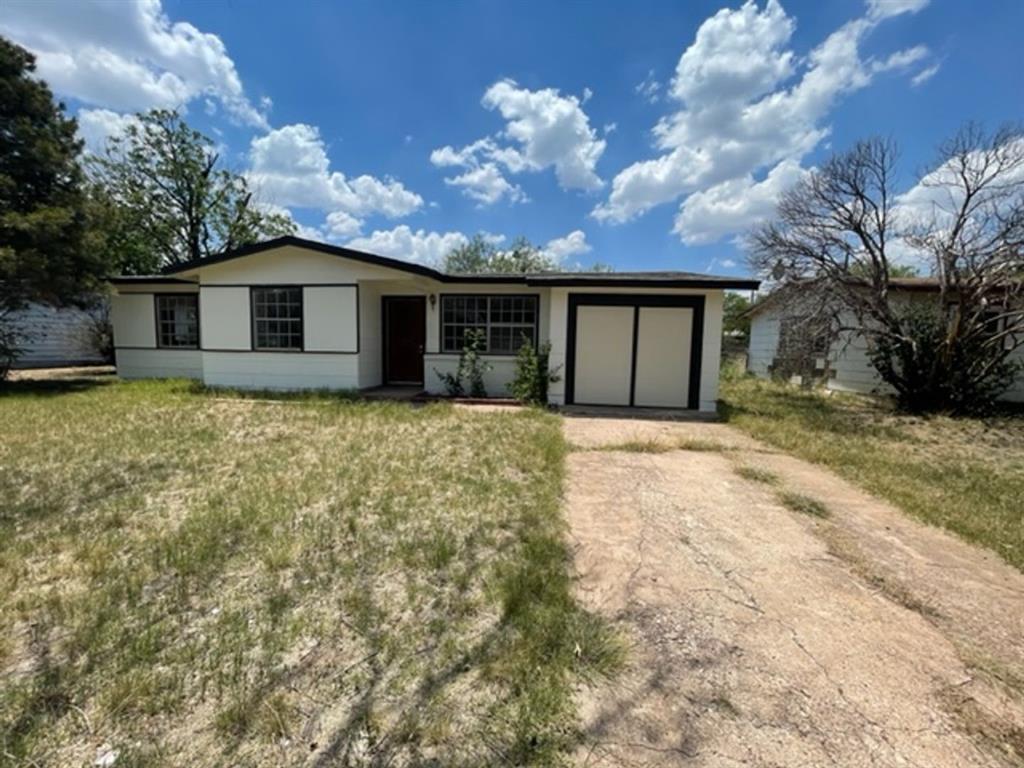 a front view of house with yard and trees in the background