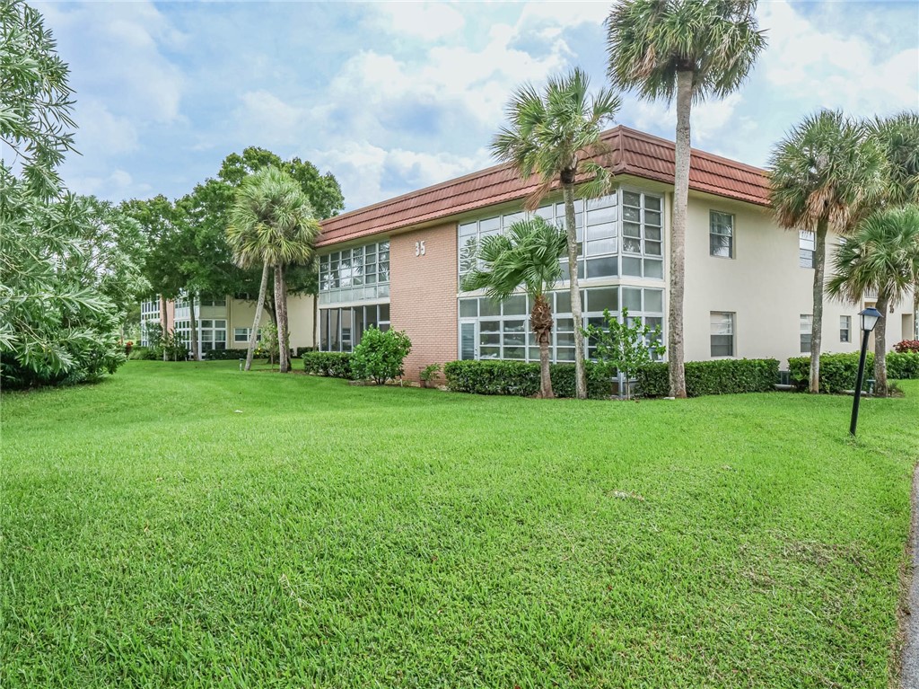 a view of a house with a yard and palm trees