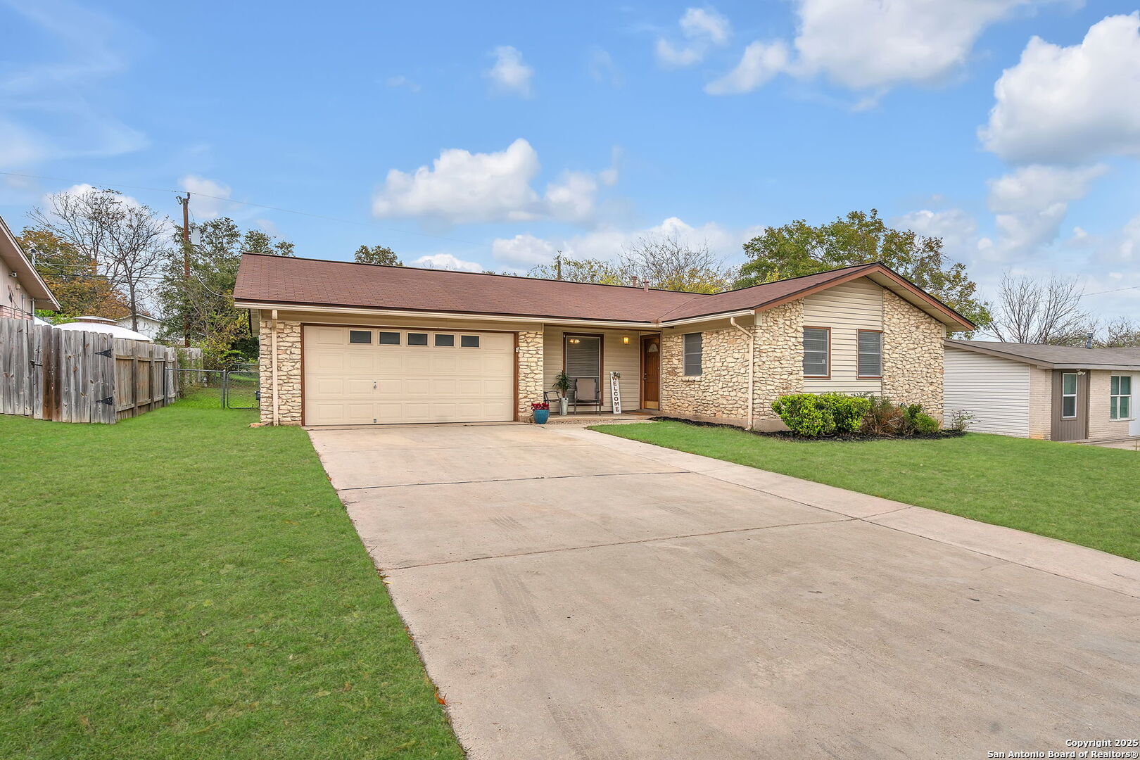 a view of house in front of a big yard with large trees