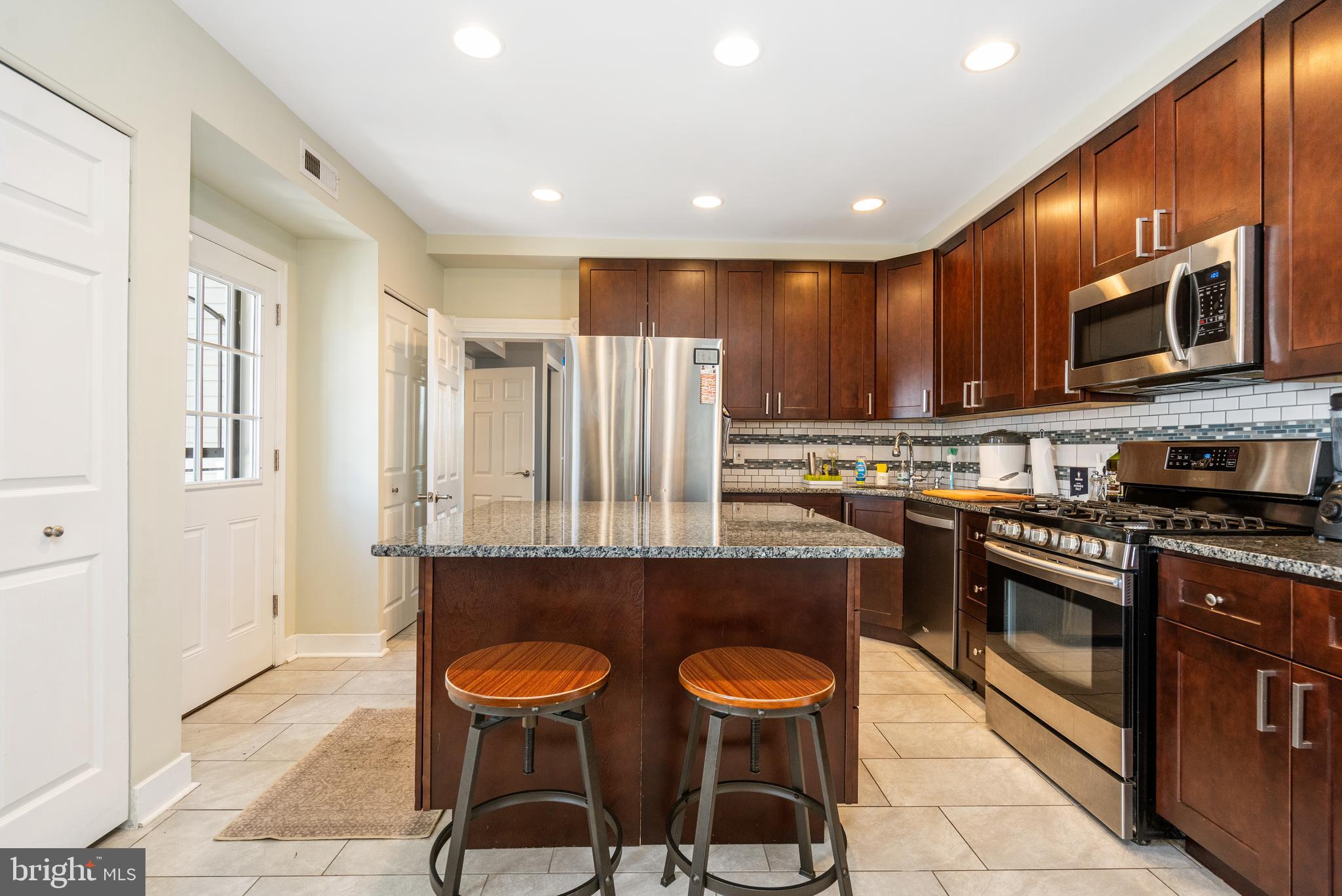 a kitchen with stainless steel appliances a table chairs refrigerator and microwave