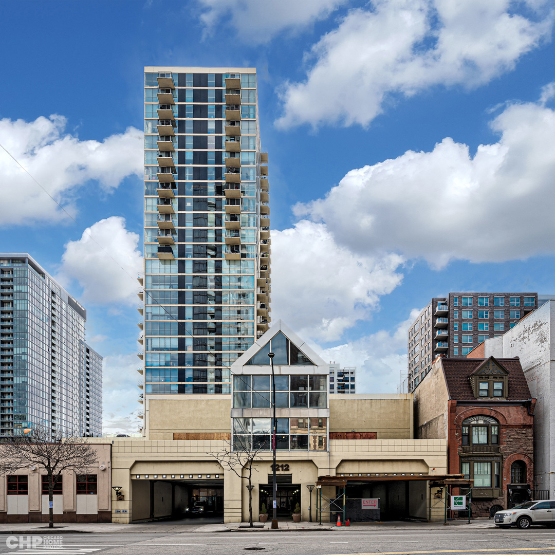 a front view of a building with lot of cars and trees