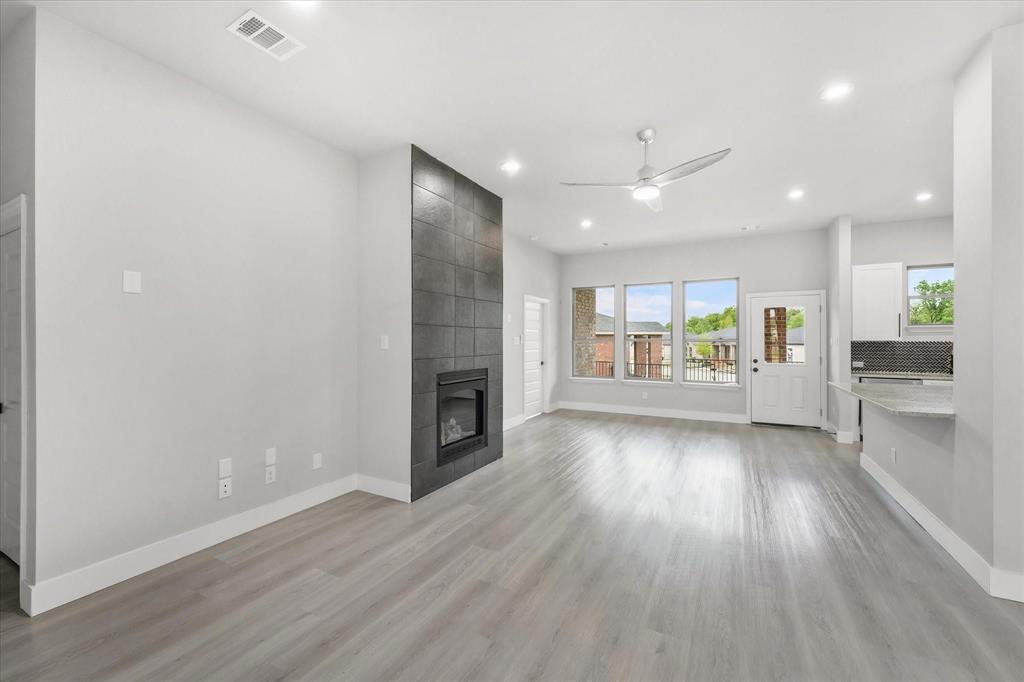 an empty room with wooden floor and a kitchen