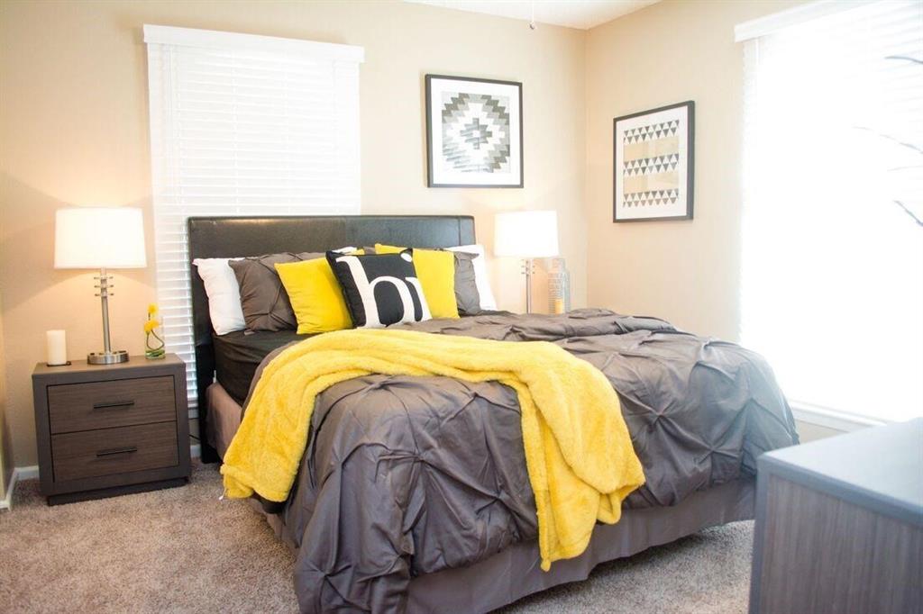 a bed sitting in a bedroom and lamp next to a window