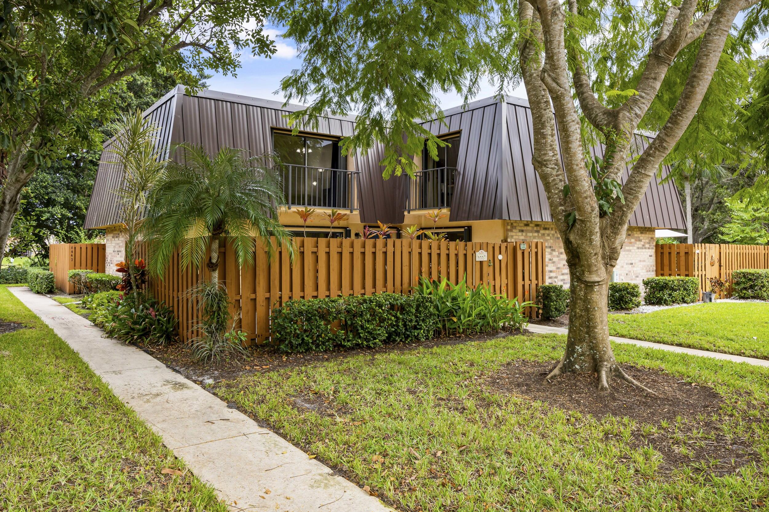 a view of a house with wooden fence next to a yard