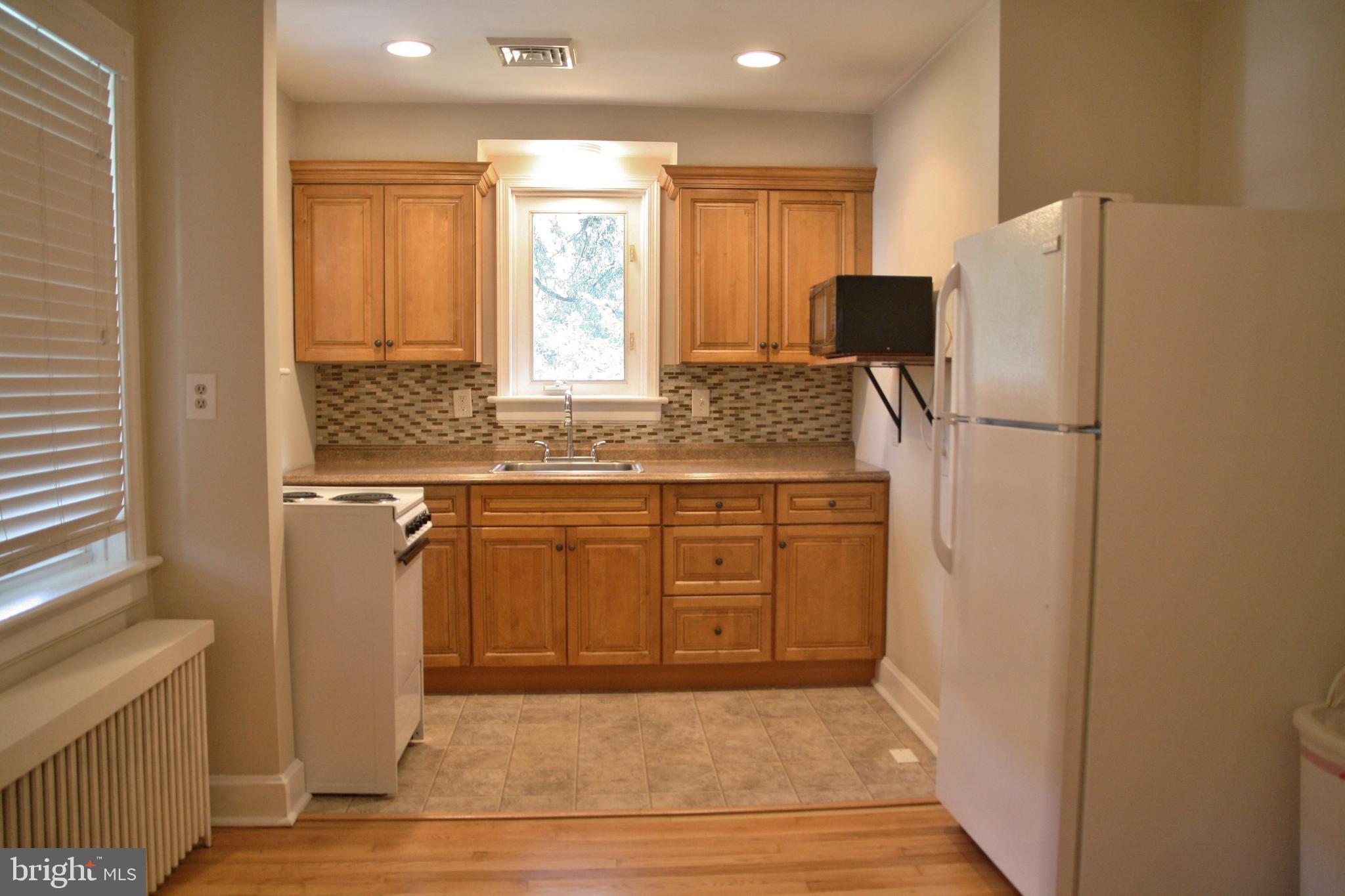 a kitchen with stainless steel appliances granite countertop a refrigerator a sink and white cabinets