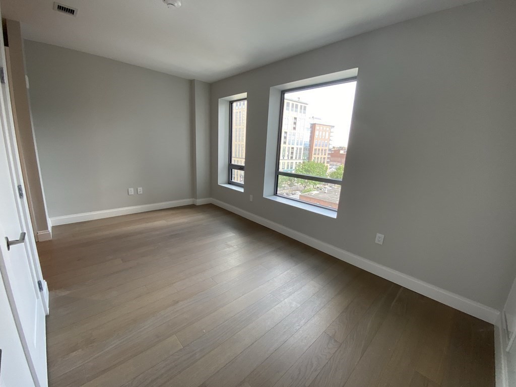 an empty room with wooden floor and windows