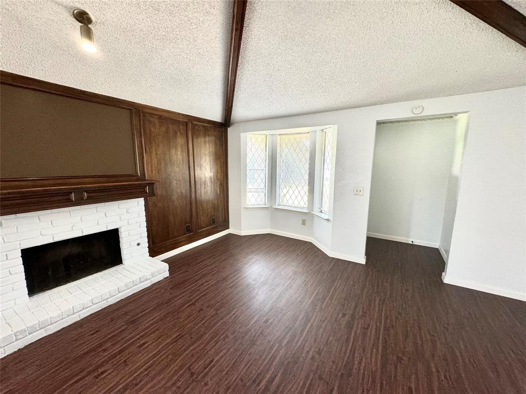 a view of an empty room with wooden floor and a fireplace