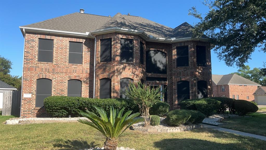 a view of a brick house with a yard and plants