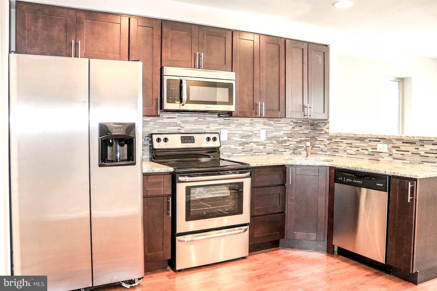 a kitchen with stainless steel appliances granite countertop a stove a refrigerator and a microwave