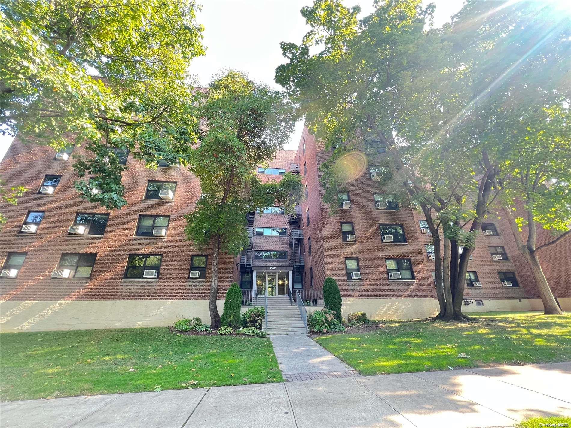 a view of a brick building next to a yard with large trees