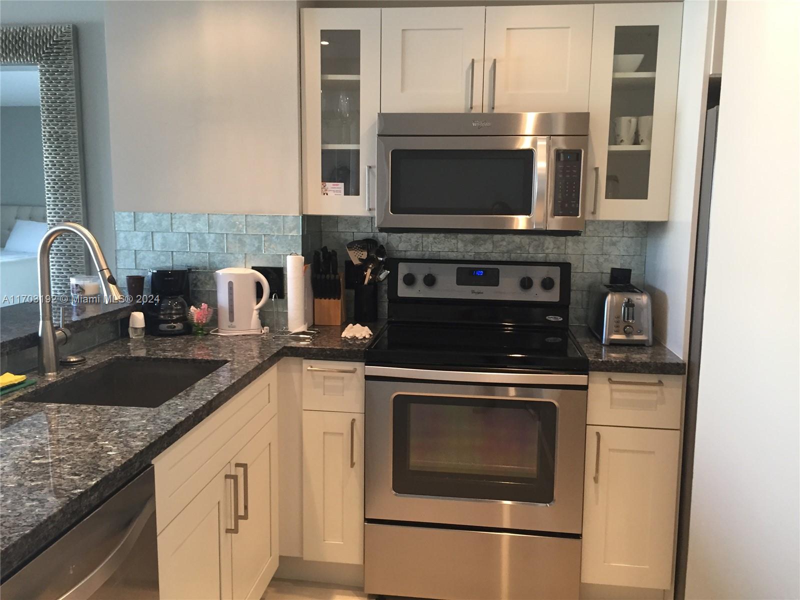 a kitchen with granite countertop a sink and a stove top oven