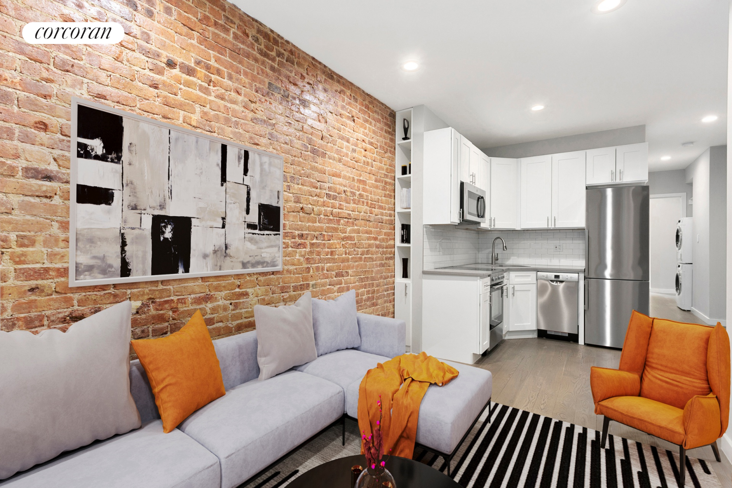 a living room with stainless steel appliances furniture a fireplace and a kitchen view