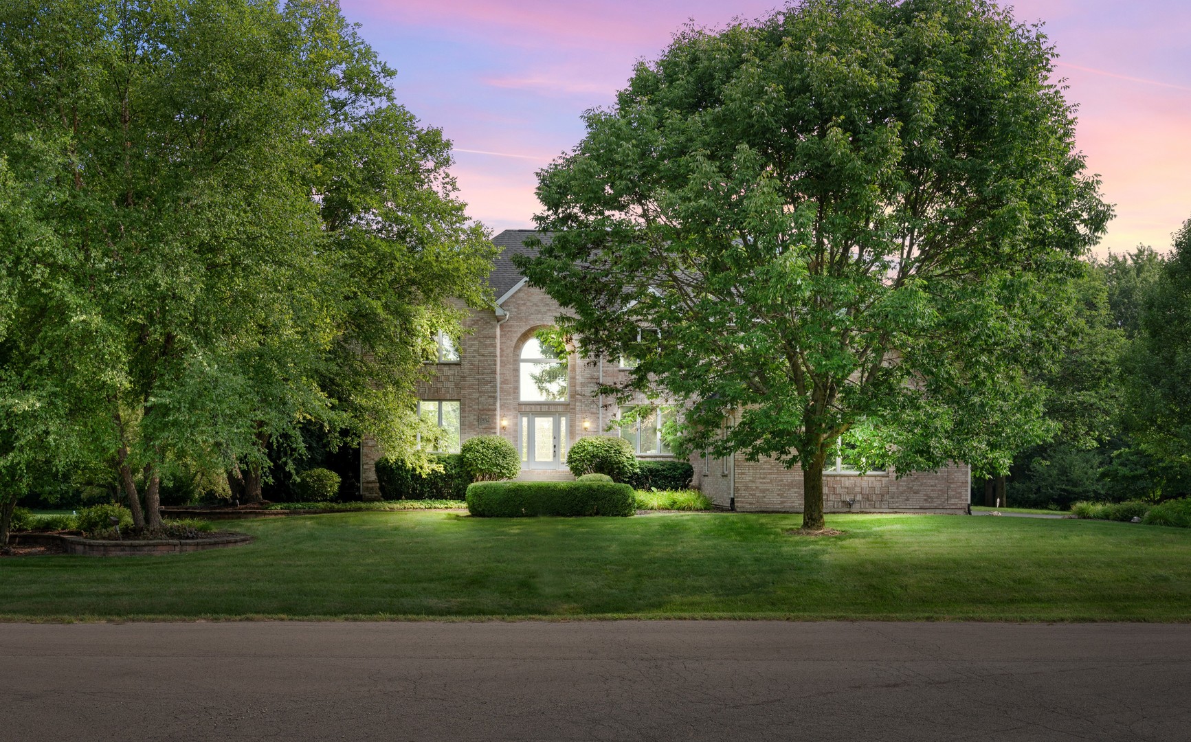 a view of a house with a big yard and large trees