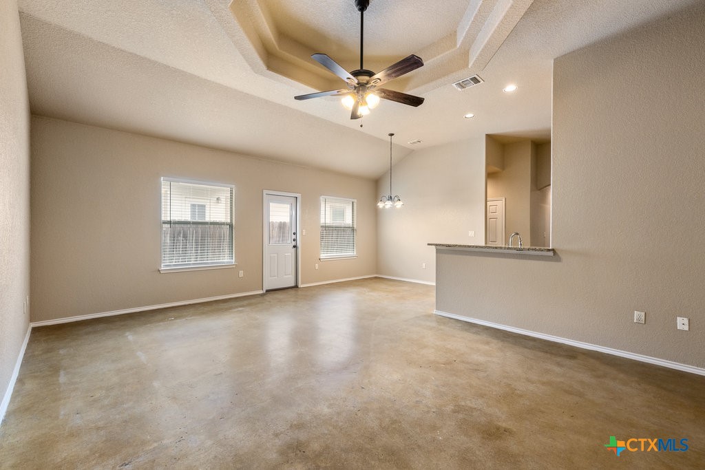 an empty room with ceiling fan and windows