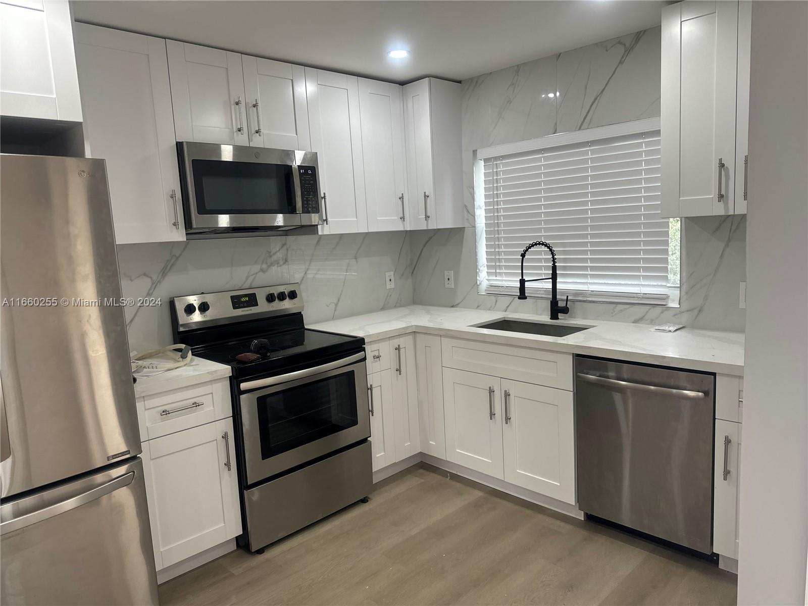 a kitchen with white cabinets stainless steel appliances and sink