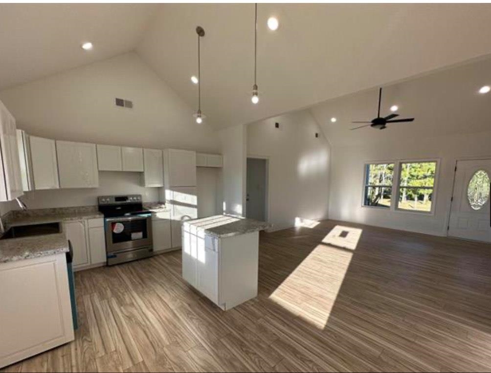 a kitchen with cabinets wooden floor and stainless steel appliances