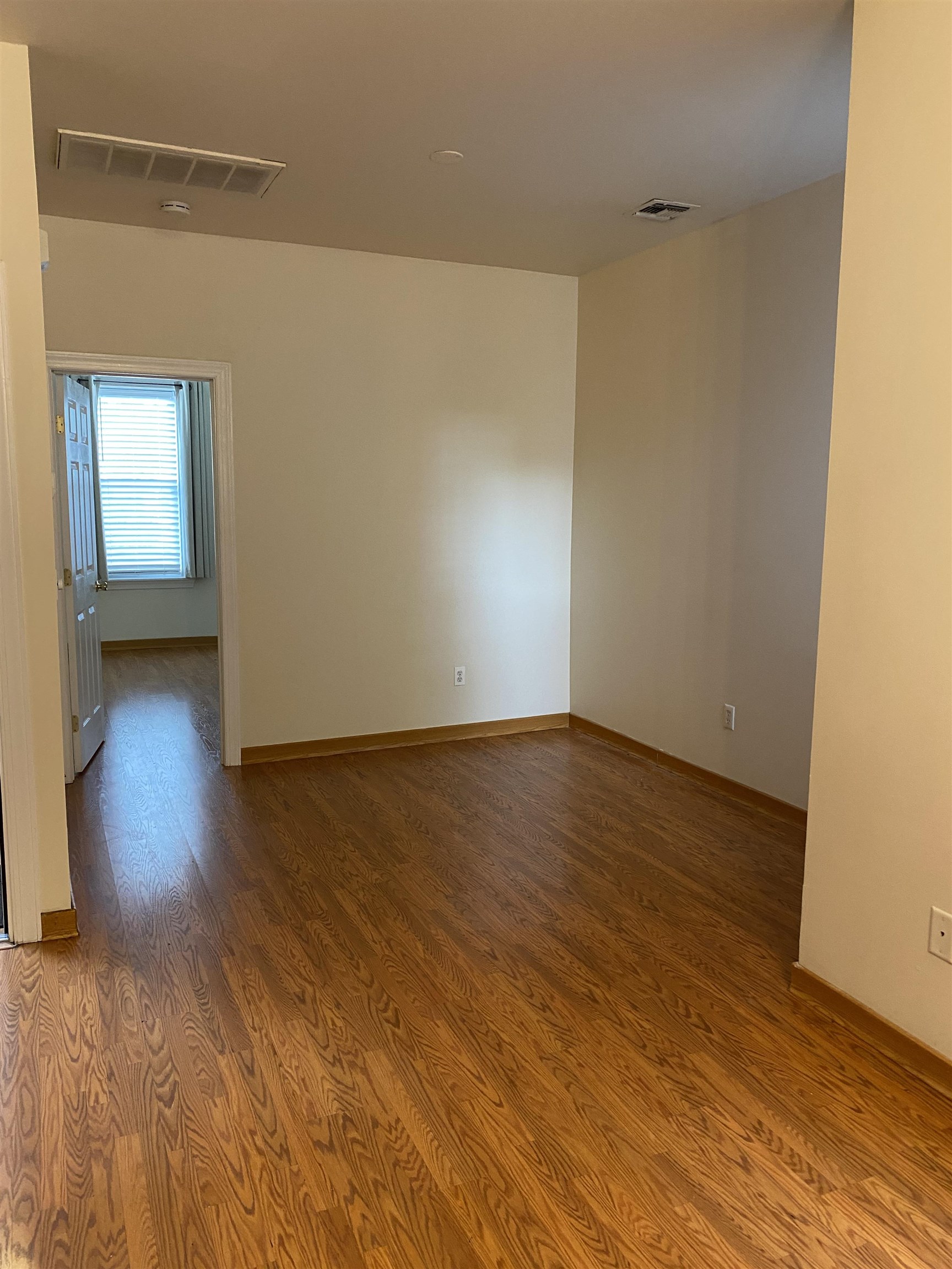 a view of an empty room with wooden floor and closet