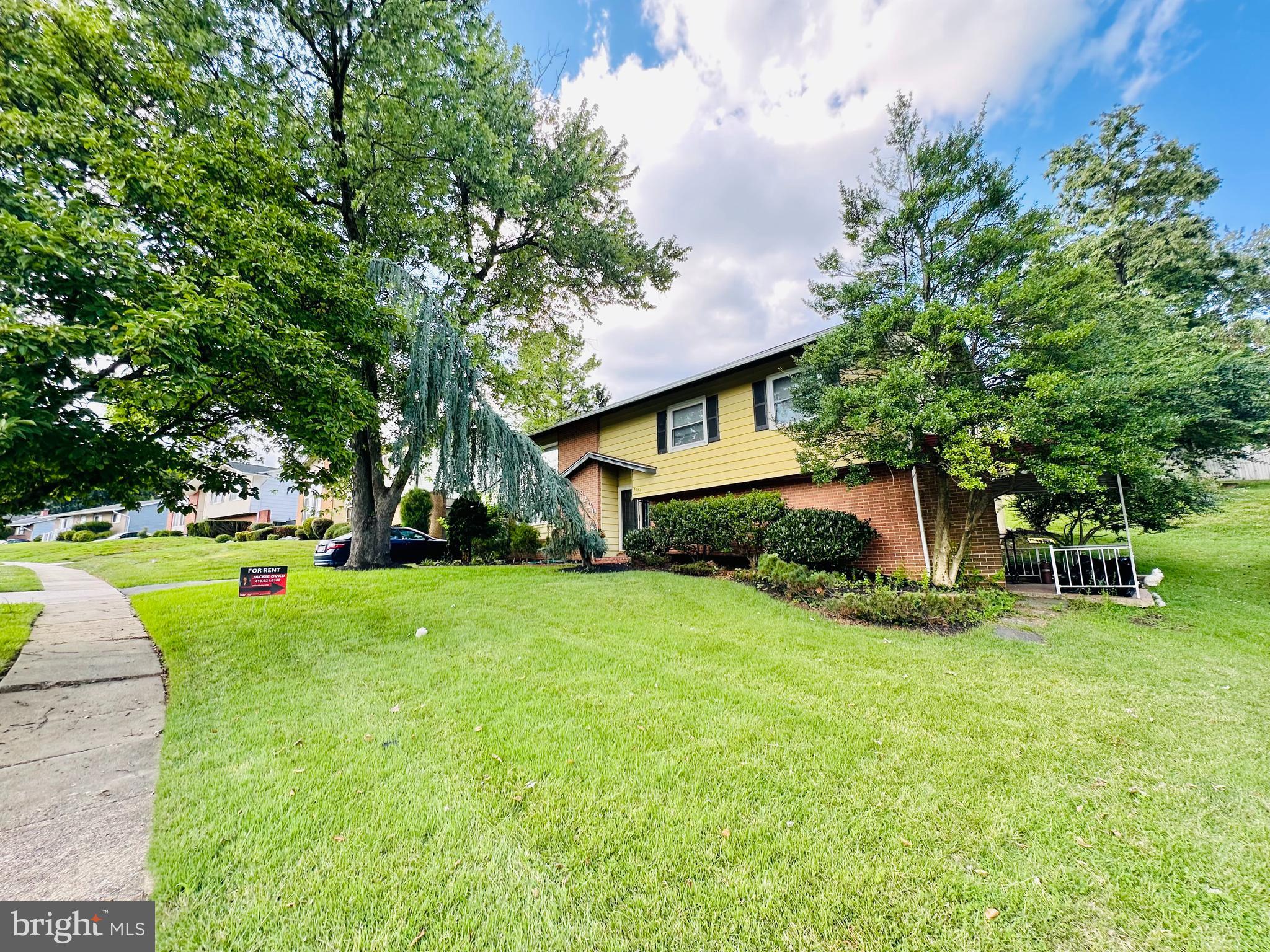 a view of a house with a big yard and large trees