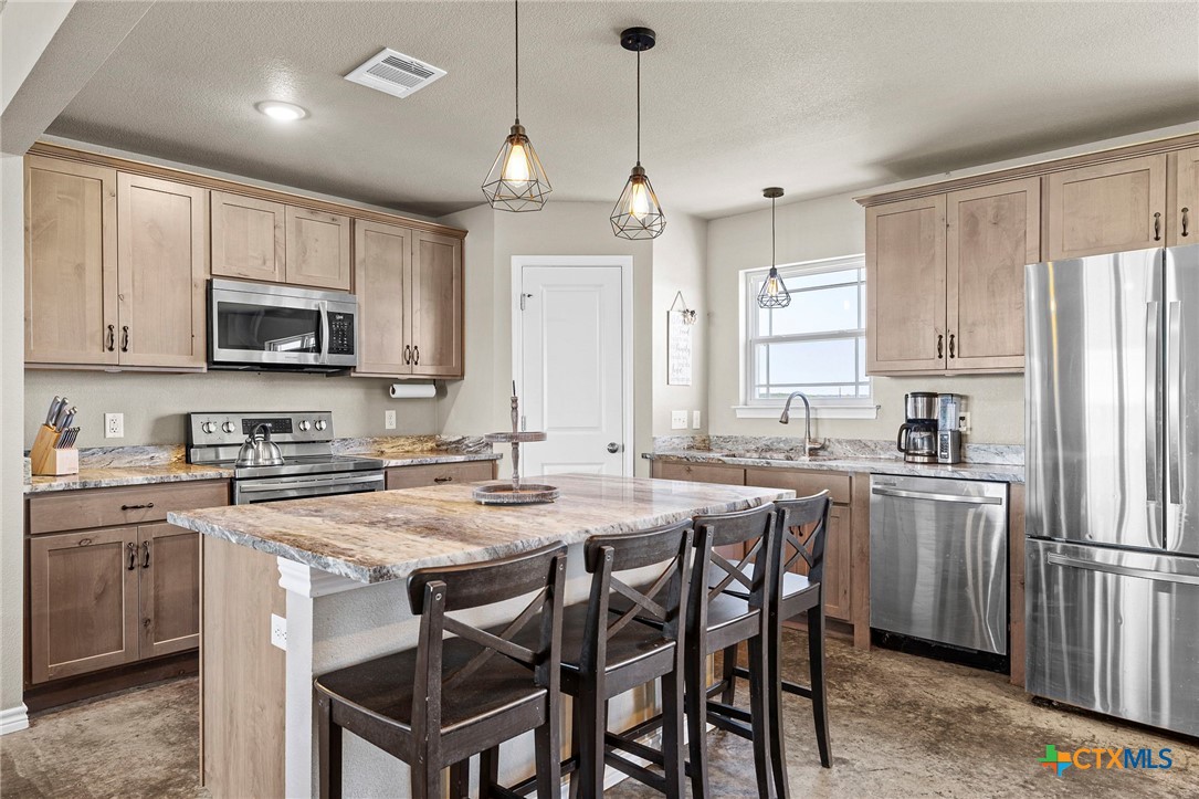 a kitchen with stainless steel appliances granite countertop a table chairs microwave and sink