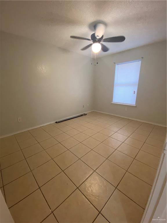 Unfurnished room featuring ceiling fan, a textured ceiling, and light tile patterned flooring