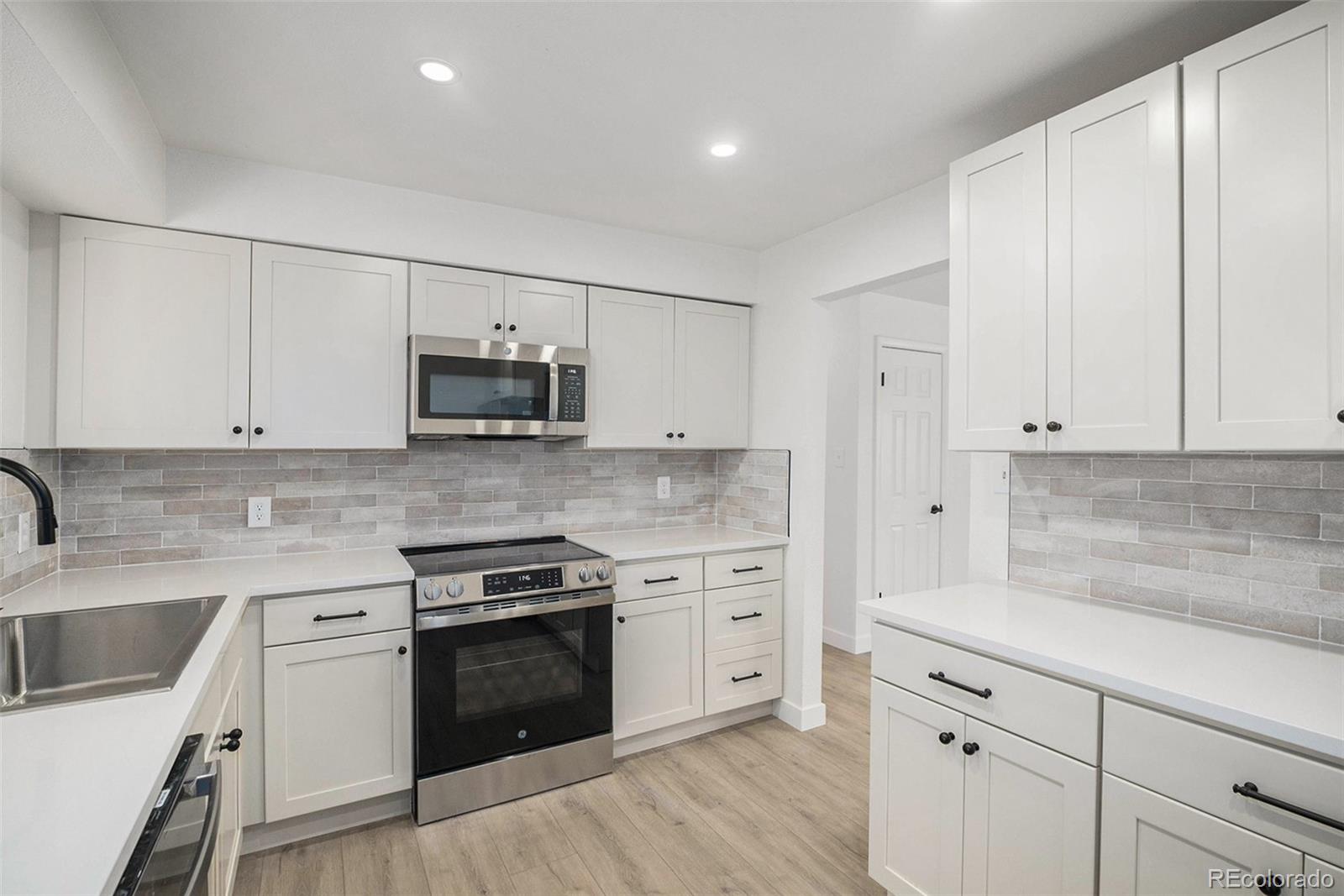 a kitchen with granite countertop white cabinets and stainless steel appliances