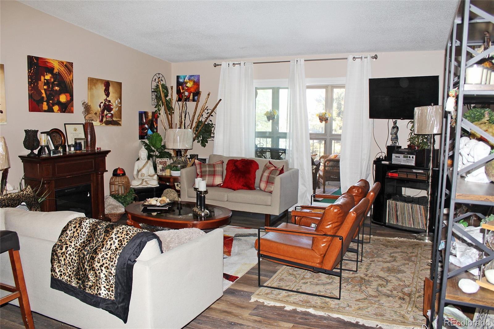 a living room with furniture a flat screen tv and a floor to ceiling window