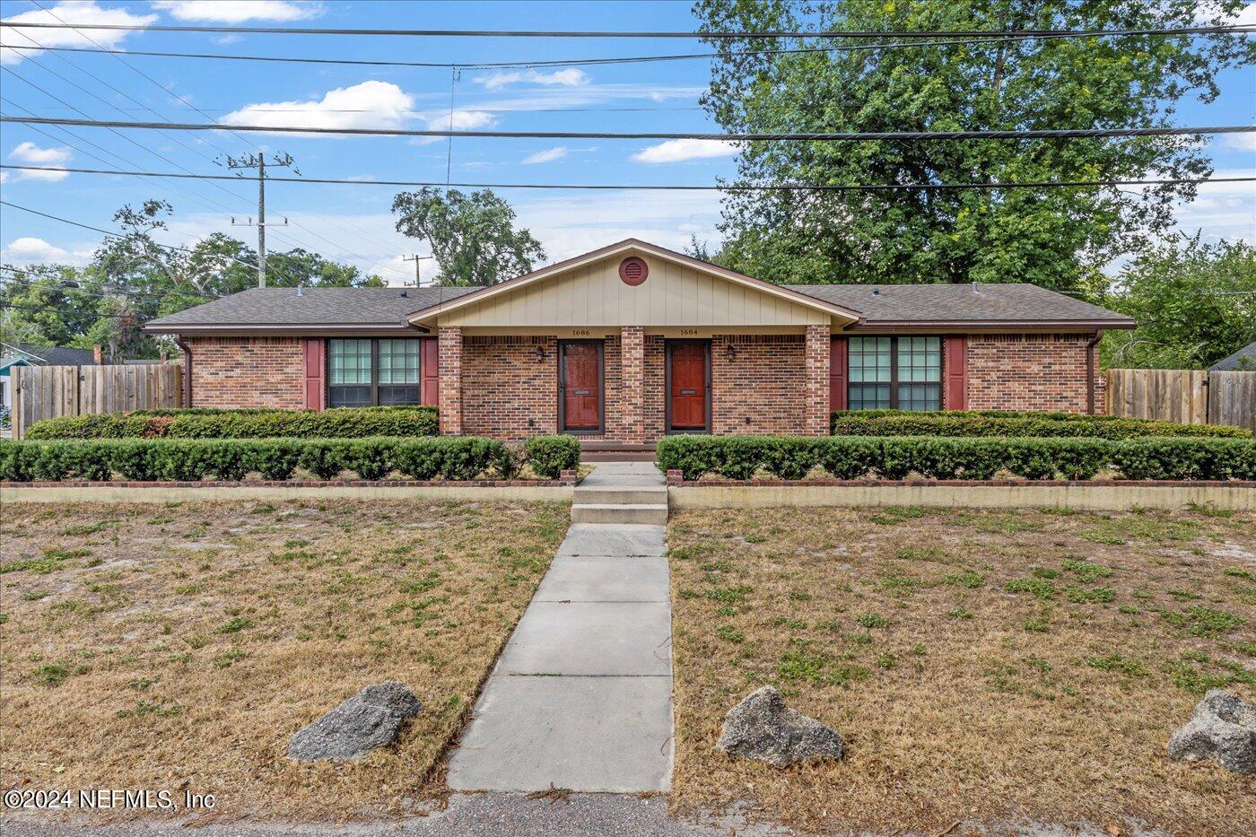 a front view of a house with a yard and potted plants