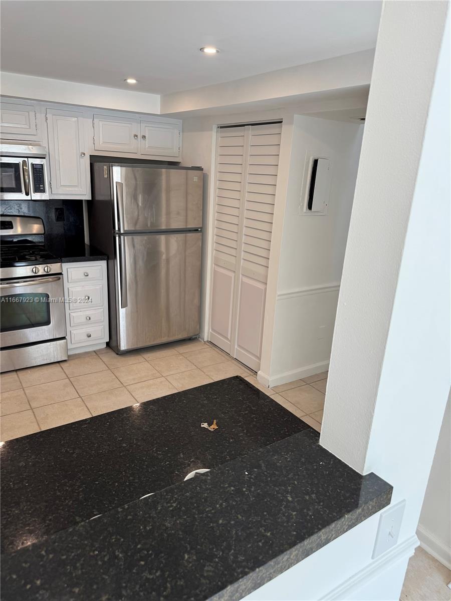 a kitchen with a refrigerator a stove top oven and white cabinets