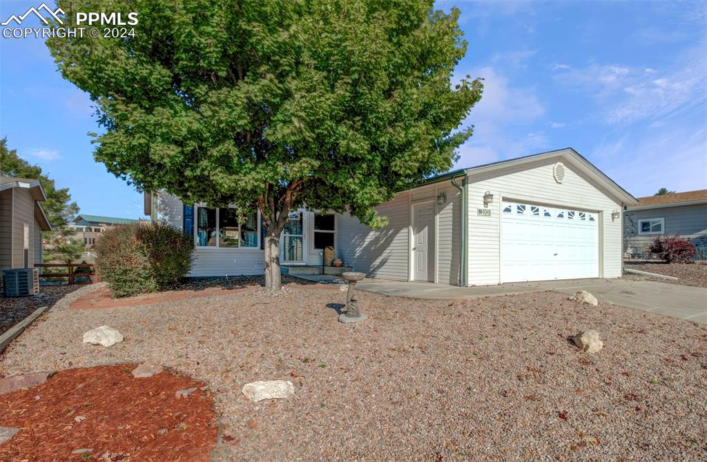 View of front of property featuring a mature tree and the garage