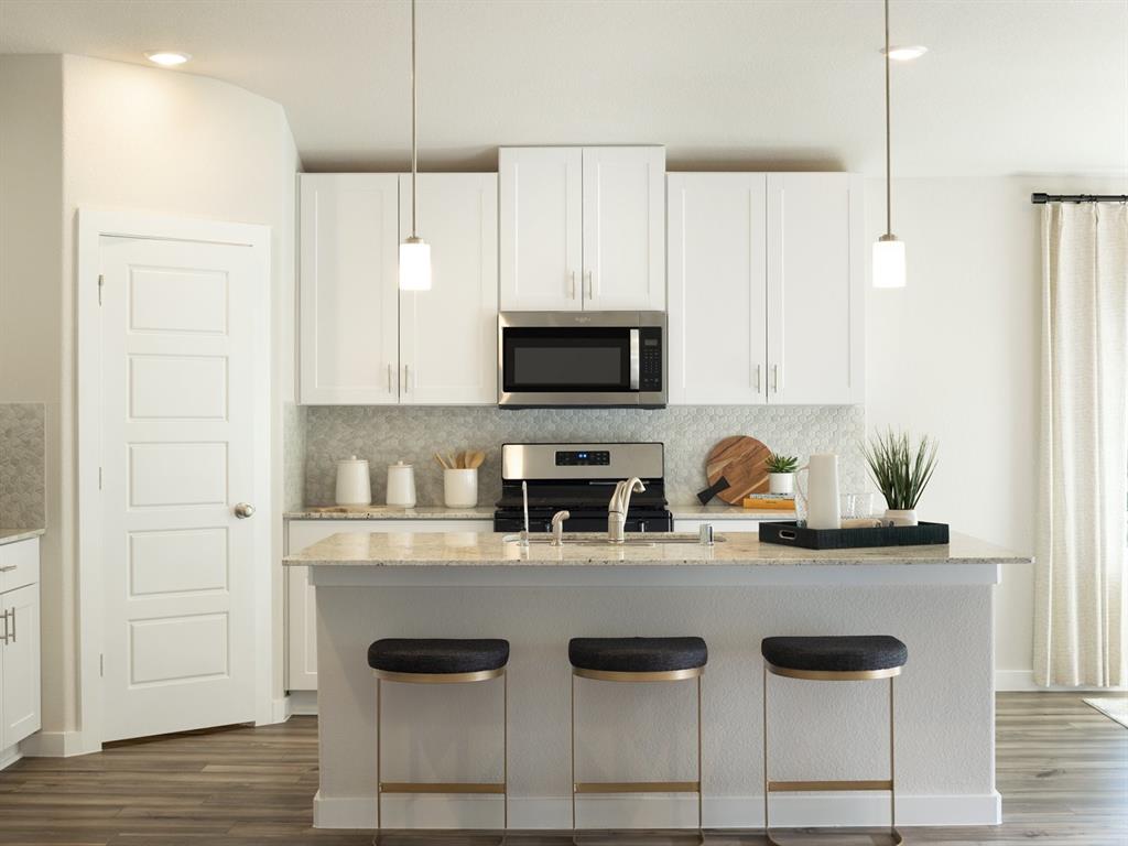 a kitchen with granite countertop a stove a sink and a microwave