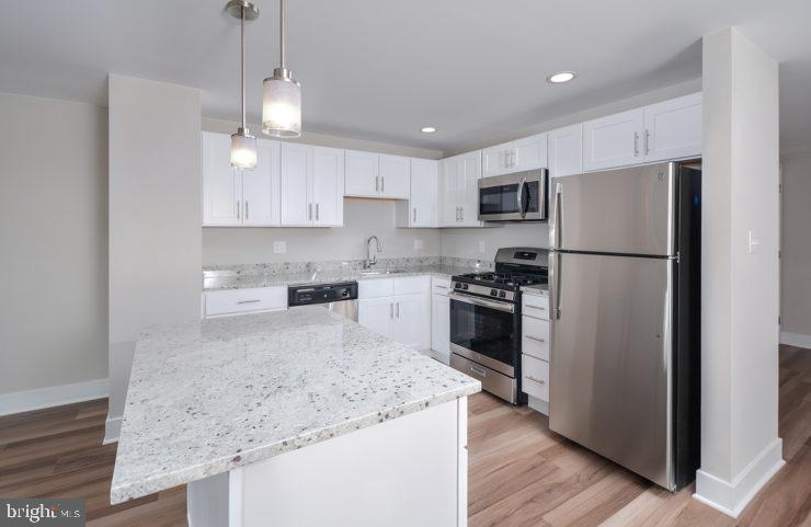 a kitchen with kitchen island white cabinets and stainless steel appliances