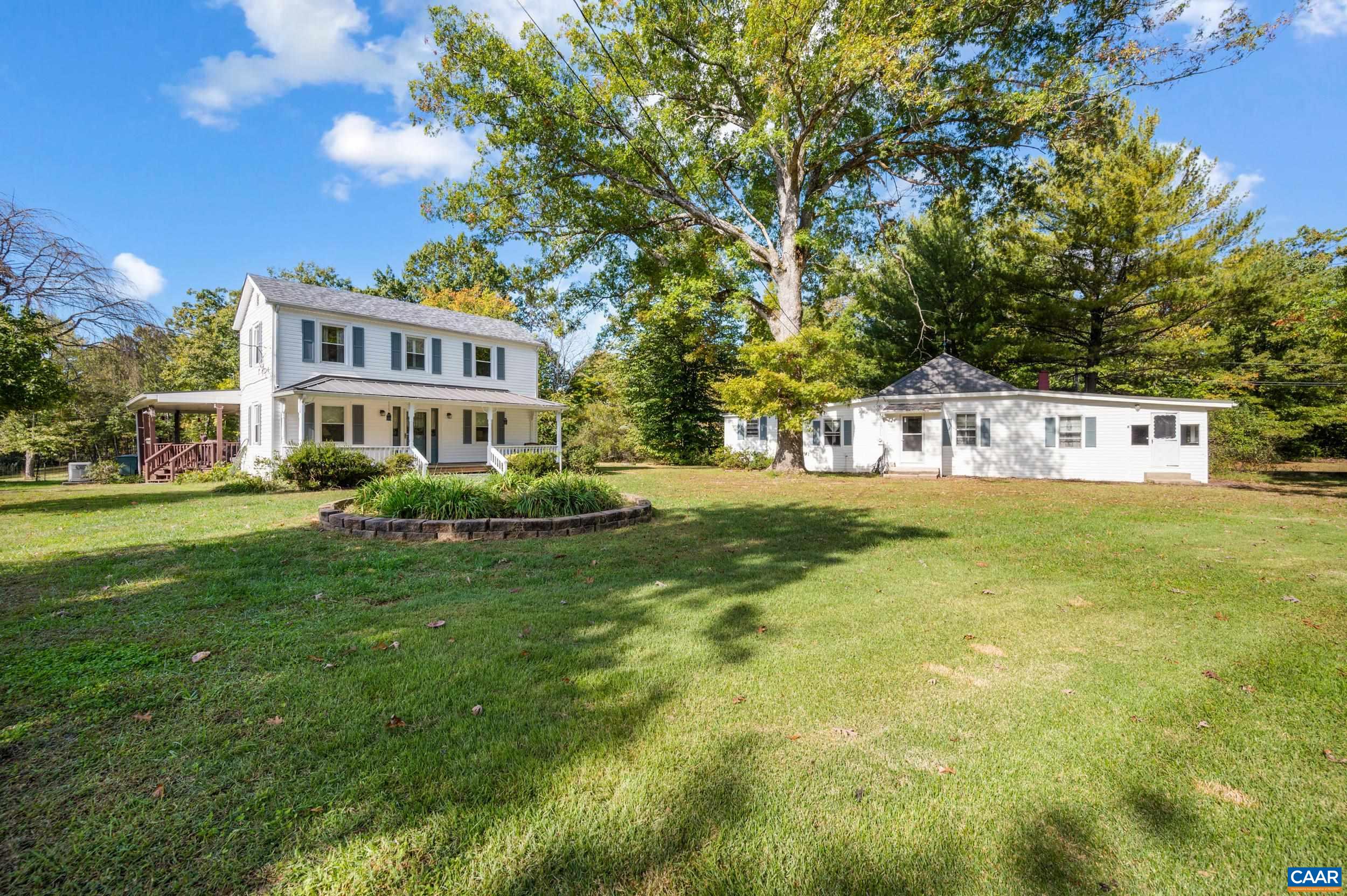 a view of a house with a big yard potted plants and large tree