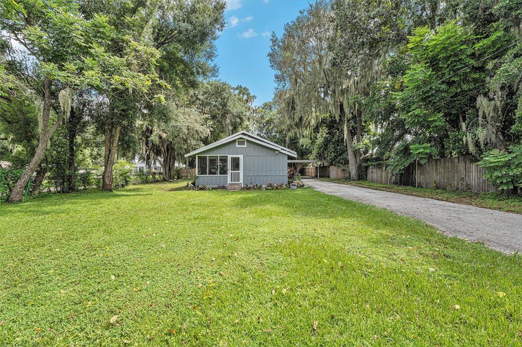 a backyard of a house with large trees and plants