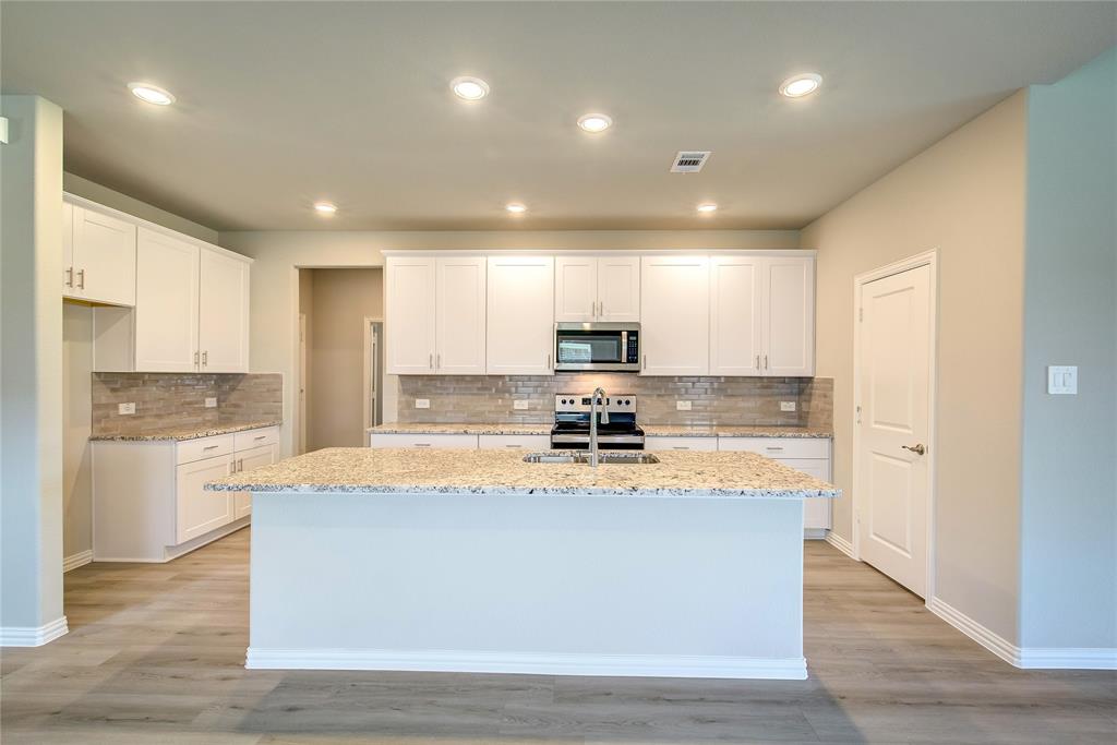 a large kitchen with stainless steel appliances granite countertop a lot of counter space and wooden floor