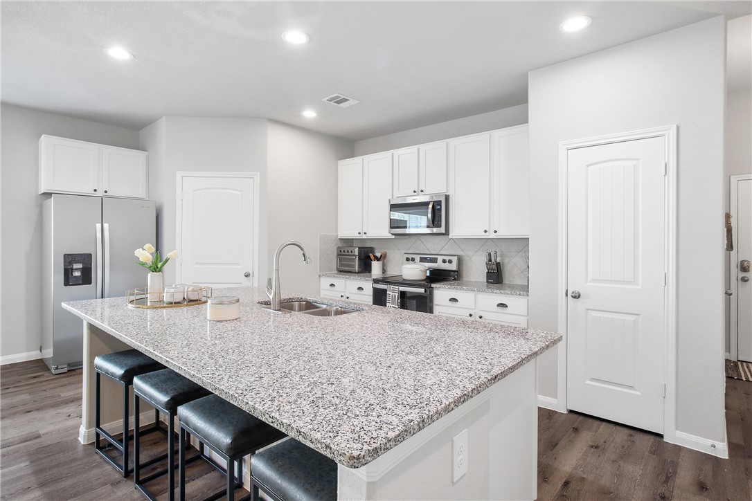 a kitchen with kitchen island granite countertop a wooden floor and white cabinets