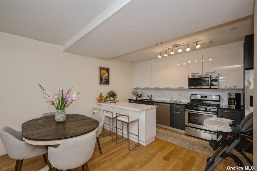 a kitchen with stainless steel appliances a dining table chairs stove and white kitchen