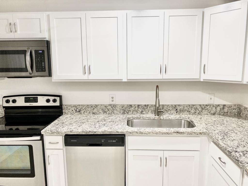 a kitchen with granite countertop white cabinets and a sink