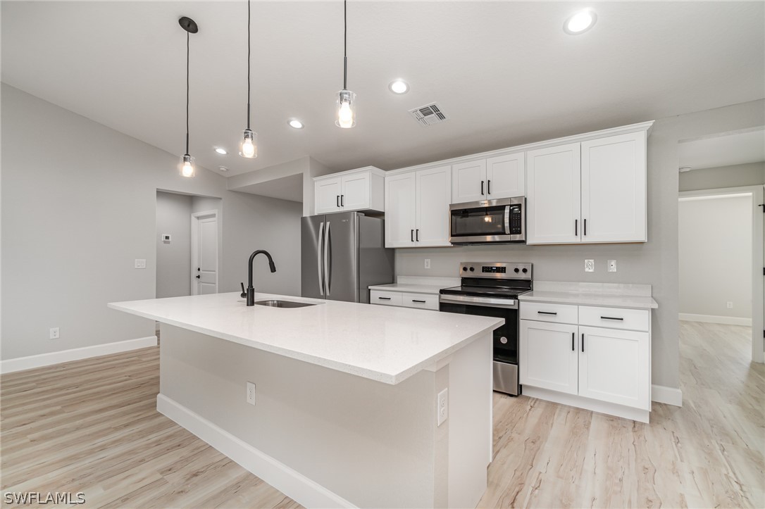 a kitchen with kitchen island a sink stainless steel appliances and wooden floor