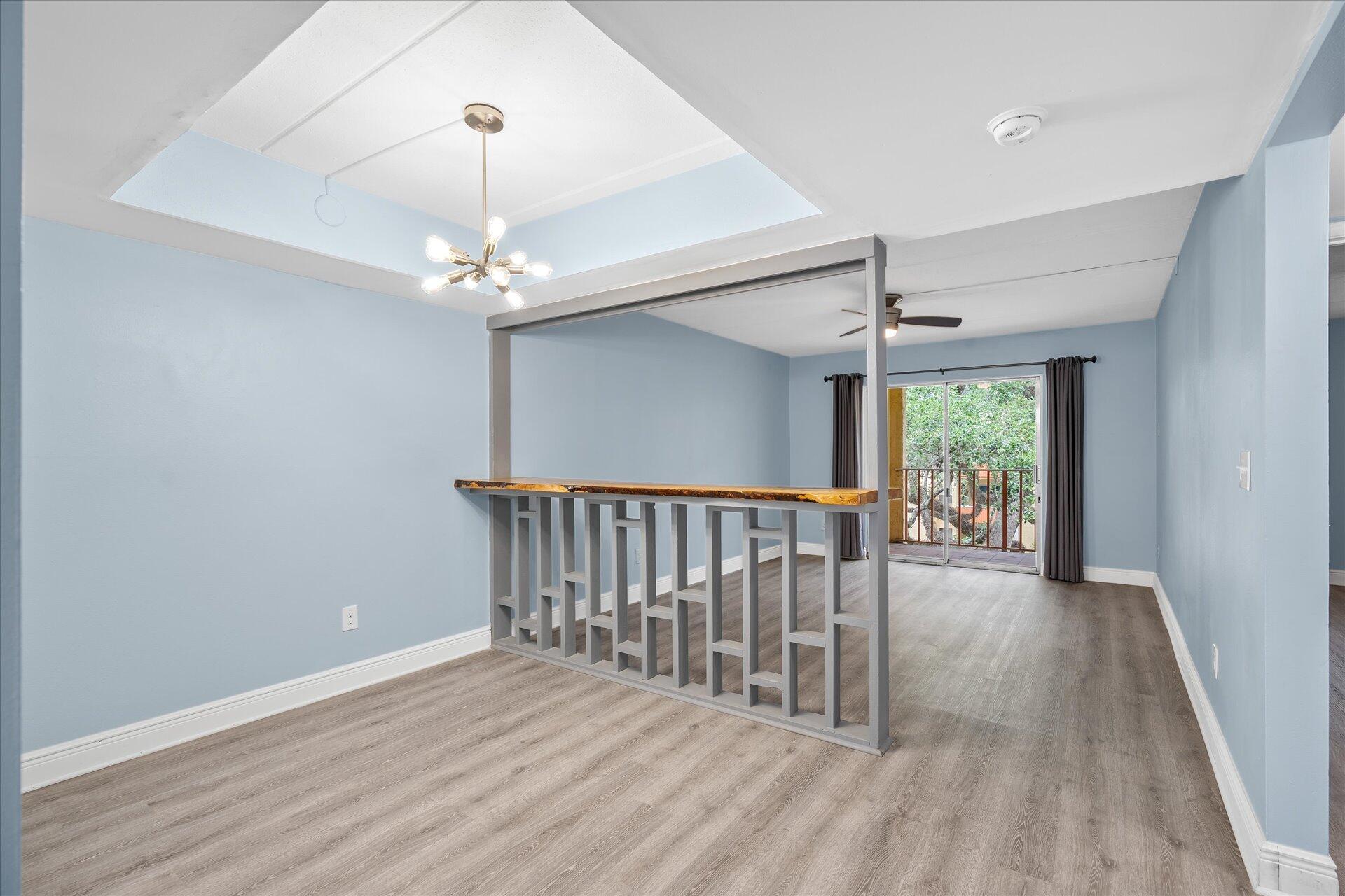 a view of a hallway with wooden floor and chandelier