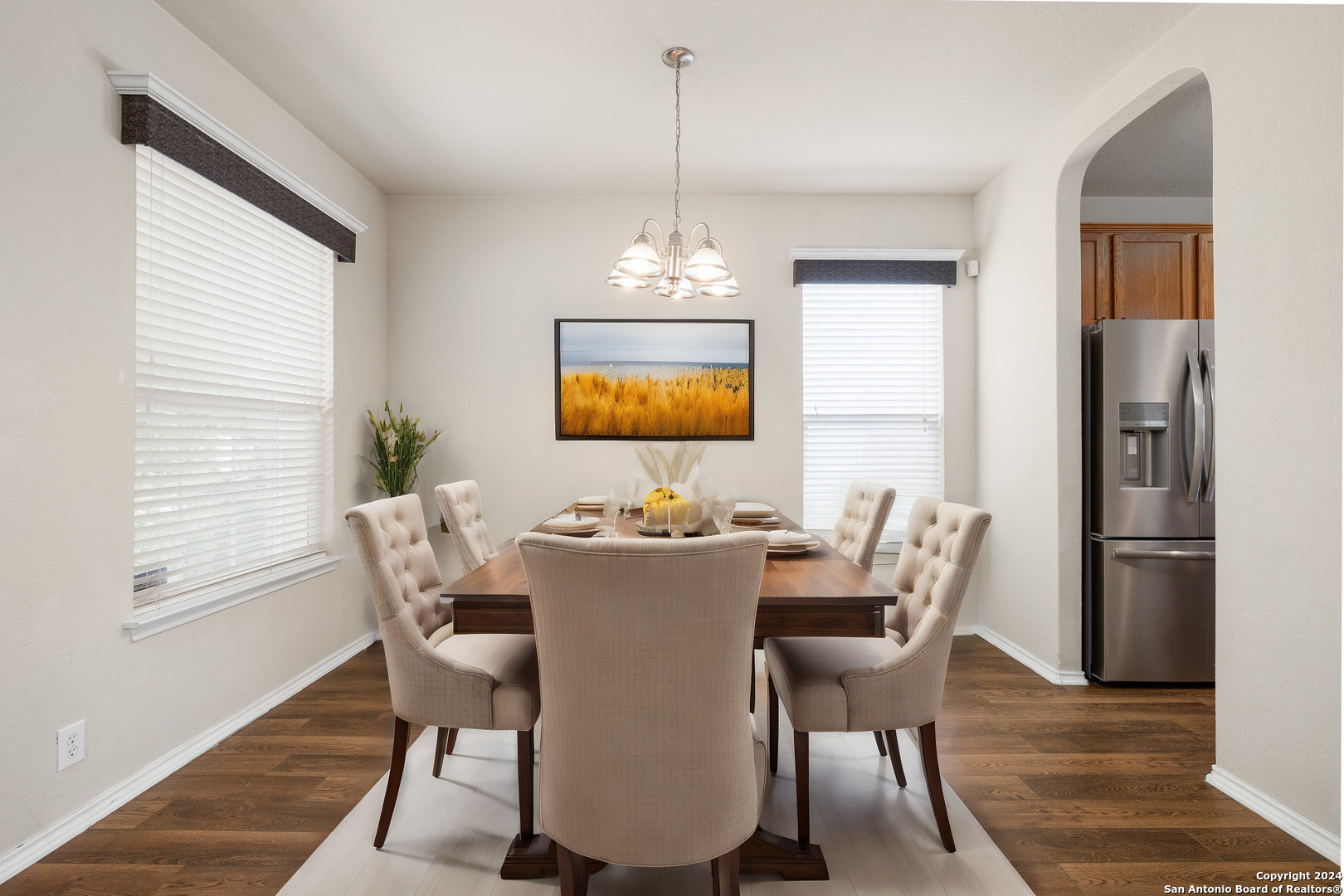 a dining room with furniture a chandelier and wooden floor