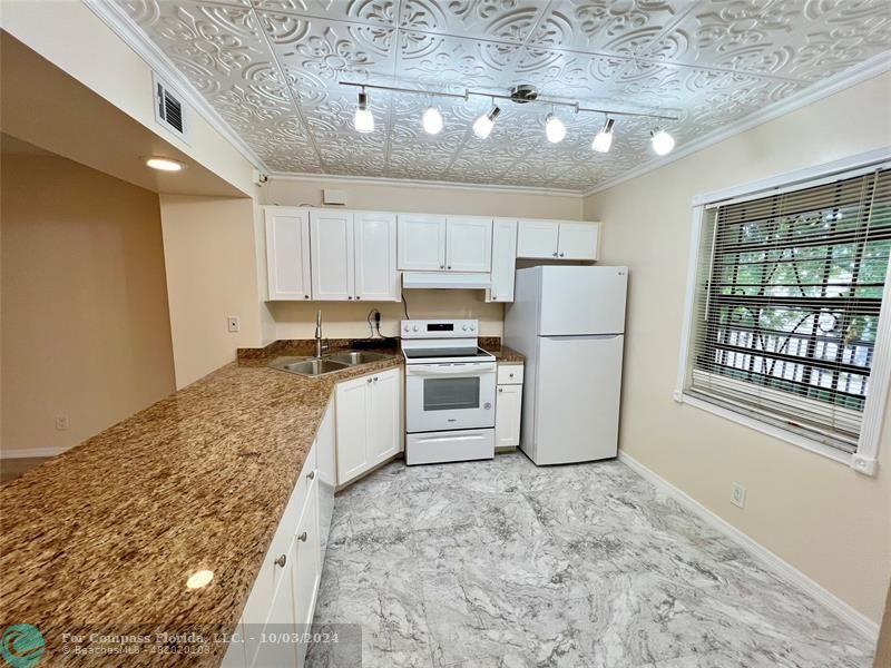 a kitchen with a refrigerator a stove top oven a sink and cabinets