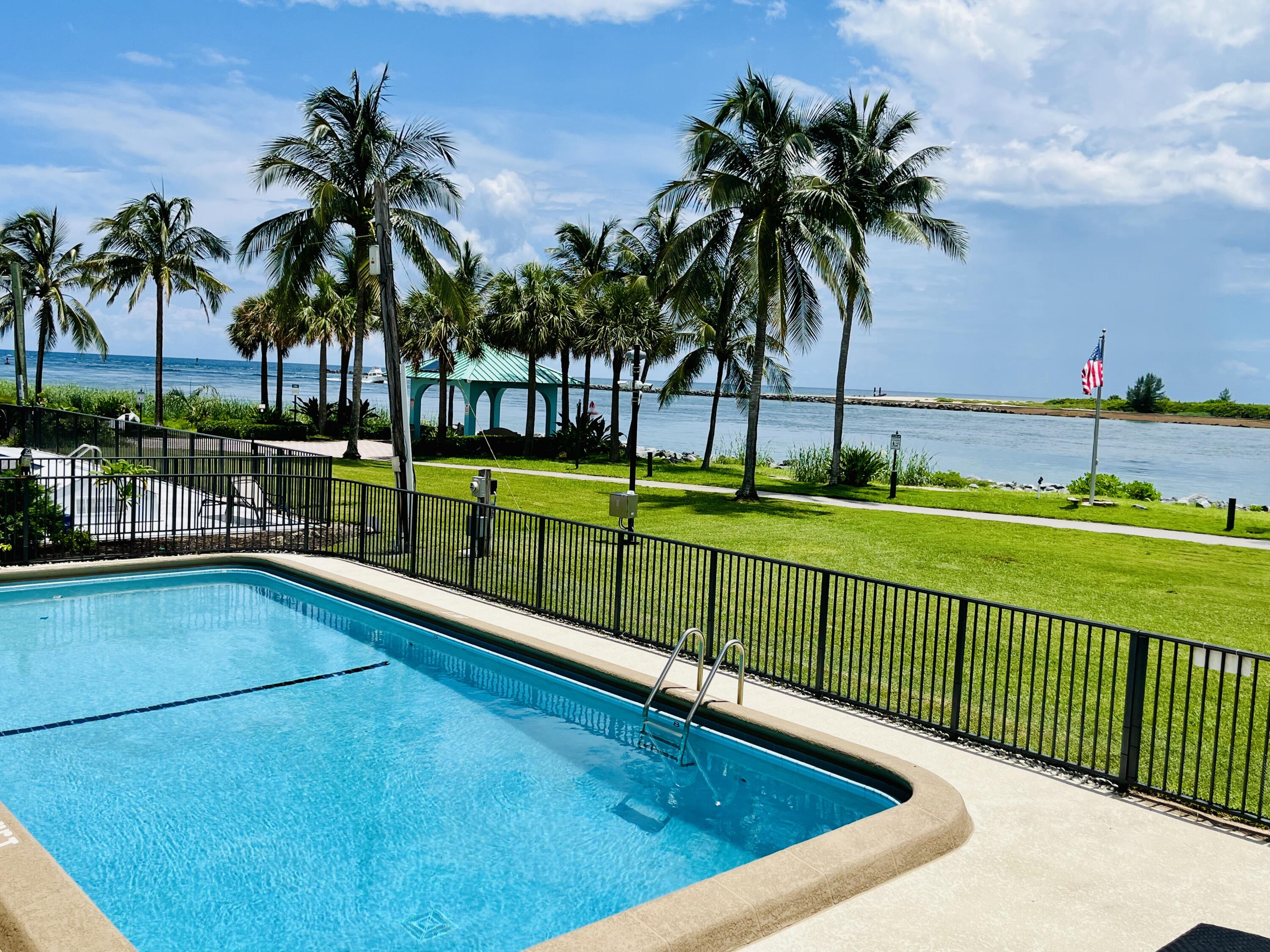 a view of swimming pool with a yard and palm trees