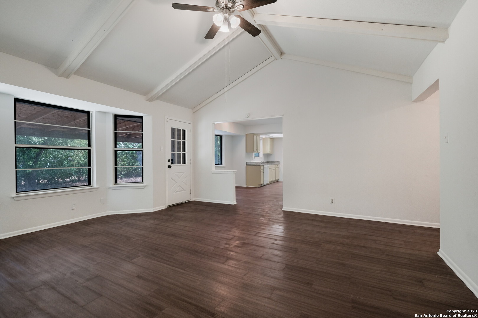 a view of an empty room with a window and wooden floor