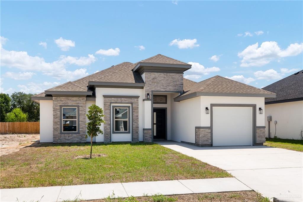 Prairie-style home featuring a garage and a front lawn