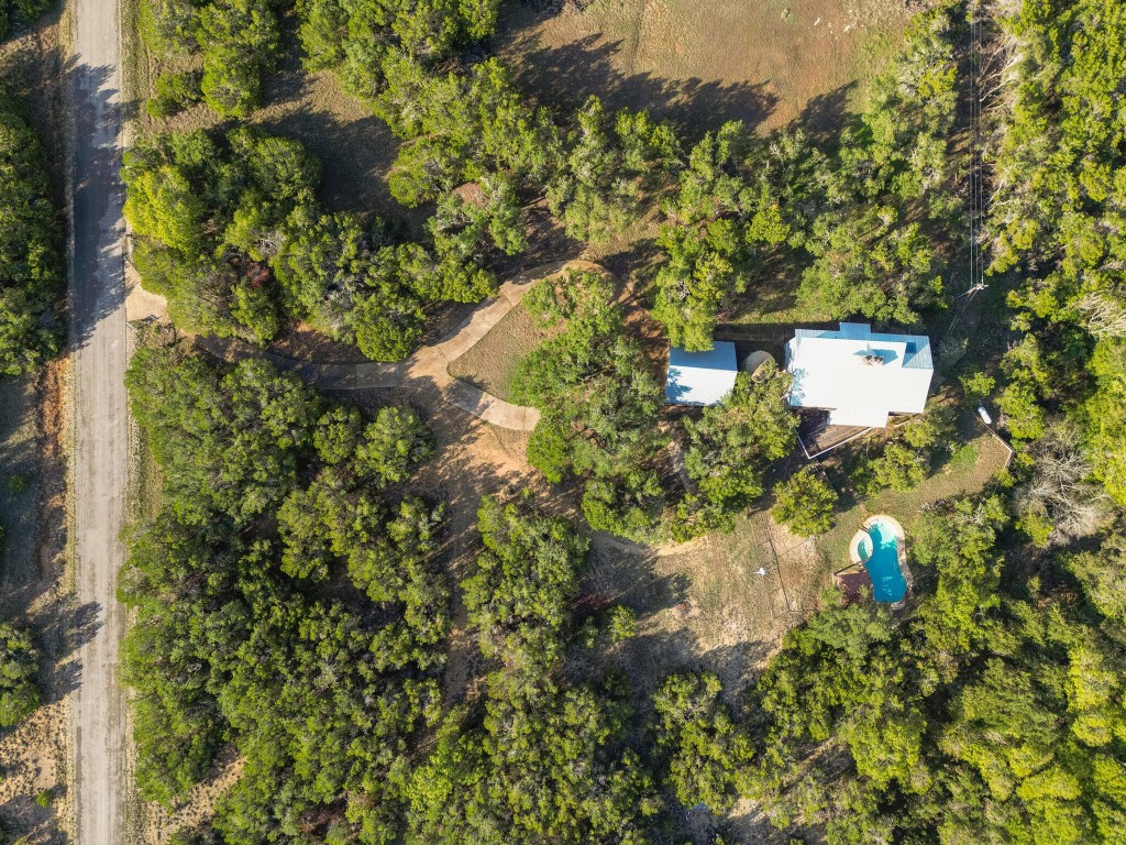 an aerial view of residential house with outdoor space and trees all around