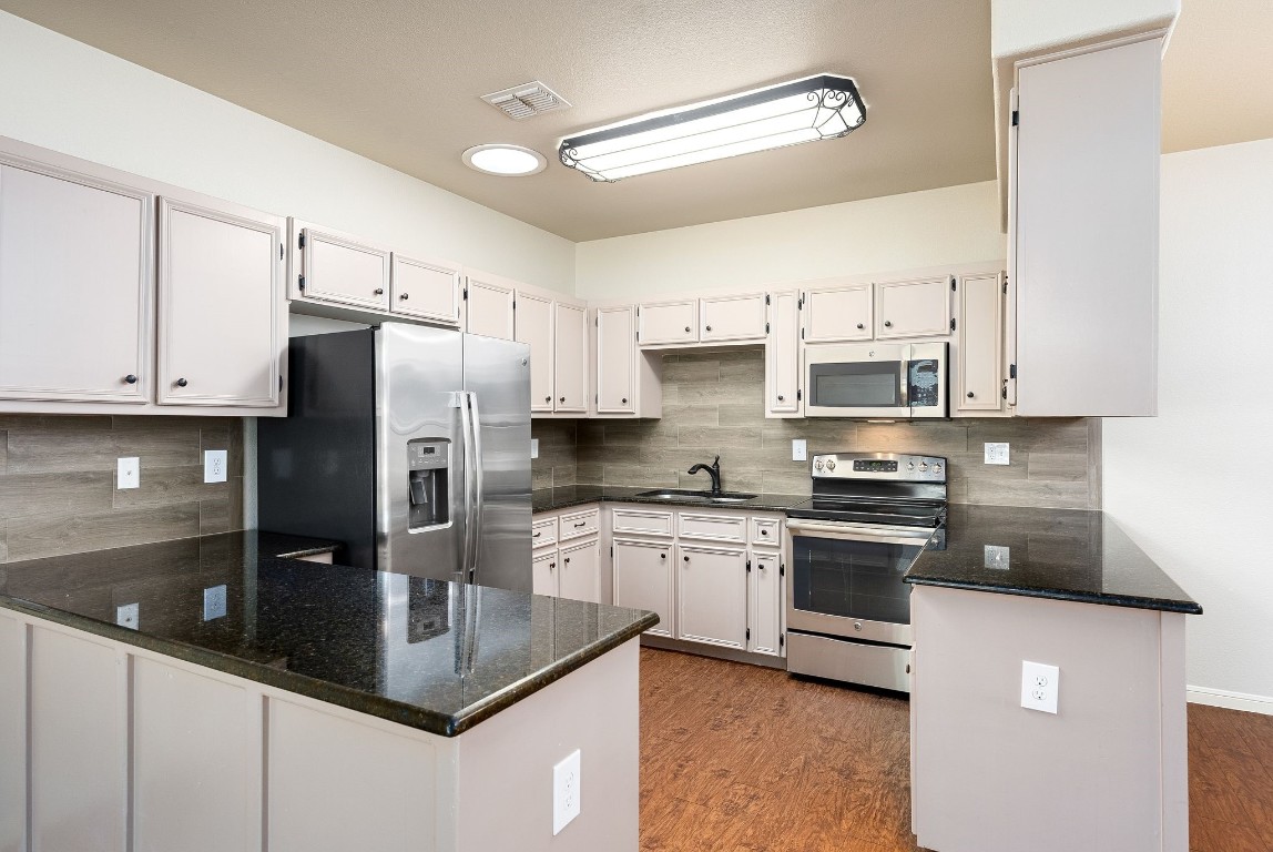 a kitchen with stainless steel appliances granite countertop a sink a stove and a refrigerator