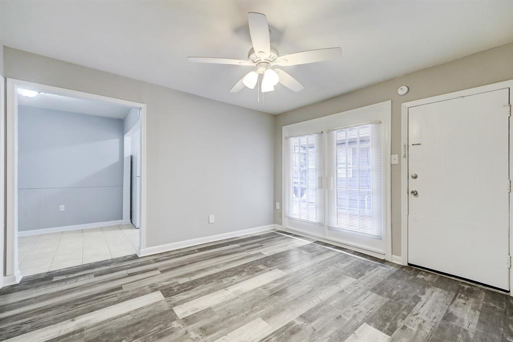 a view of an empty room with wooden floor and fan