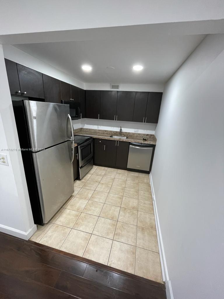 a kitchen with kitchen island a counter top space wooden floor and refrigerator