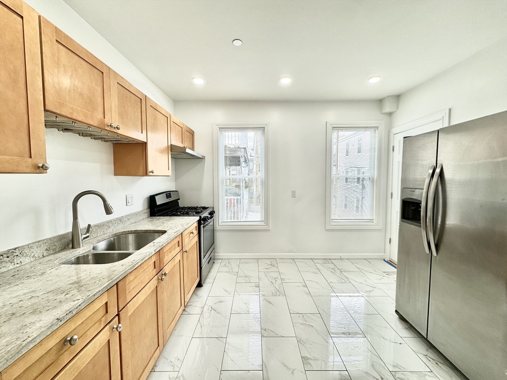 a kitchen with stainless steel appliances granite countertop a sink and a refrigerator